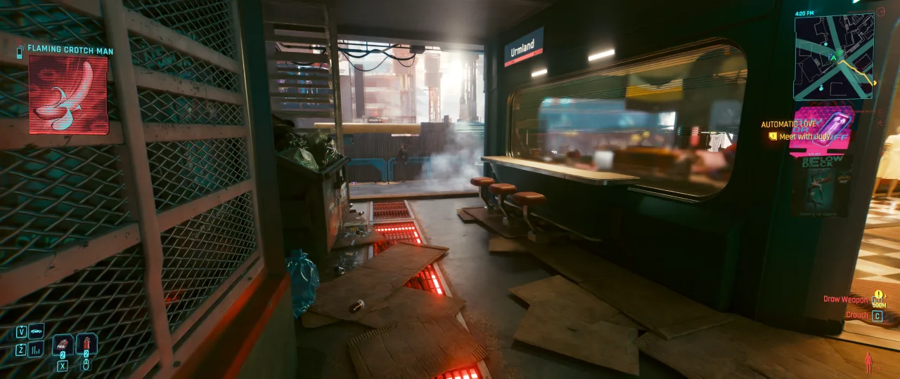 A dim, futuristic interior from *Cyberpunk 2077* shows a cluttered room with glowing floor lights, mesh partitions, and a long desk set beneath bright screens and window light, capturing the game’s gritty high-tech atmosphere during a quieter story moment.